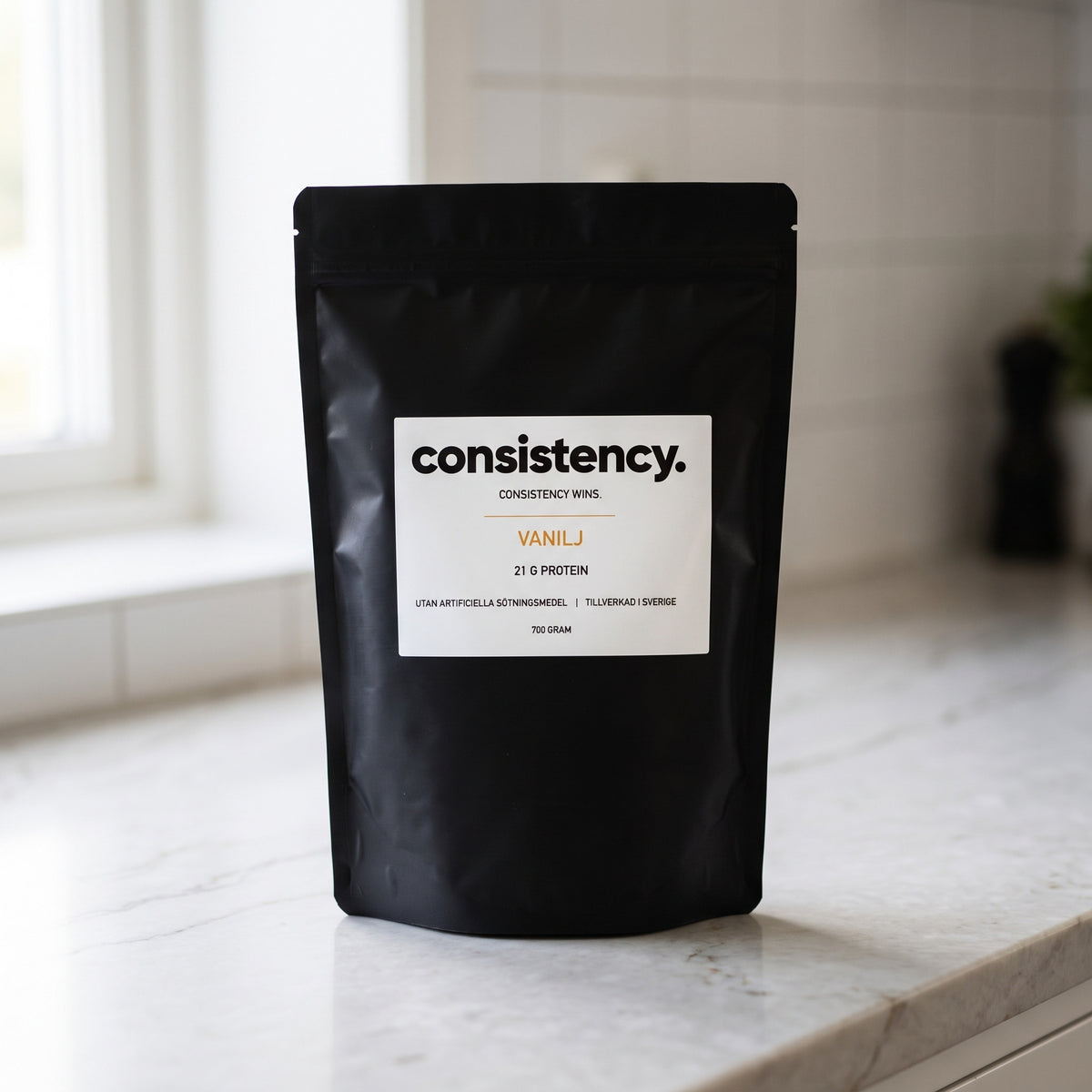 Consistency vassleprotein vanilj, svart påse på köksbänk
